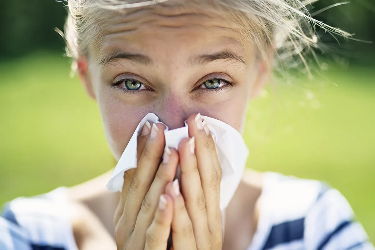 Großaufnahme einer Person, die sich die Nase mit einem Tuch putzt